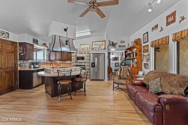 kitchen featuring lofted ceiling, open floor plan, stainless steel appliances, light countertops, and backsplash