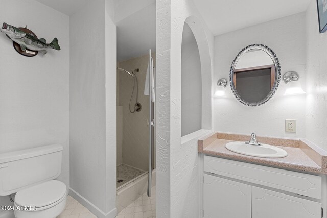 bathroom featuring tile patterned floors, vanity, a shower with door, and toilet