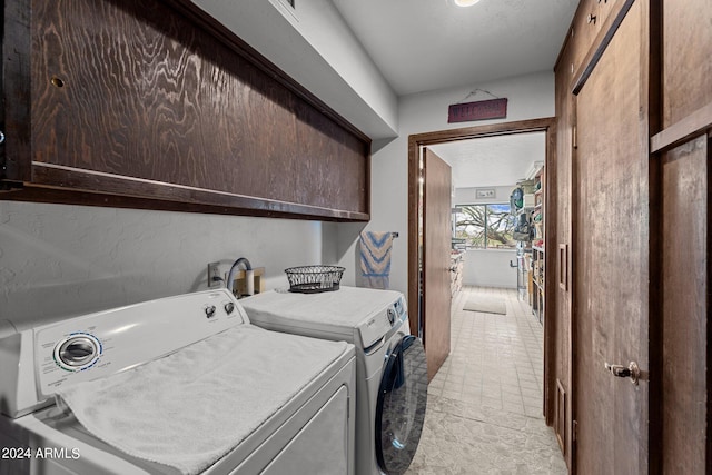 clothes washing area featuring cabinet space and separate washer and dryer