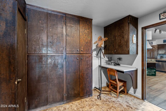 kitchen with light hardwood / wood-style flooring, dishwasher, dark brown cabinetry, and wall chimney exhaust hood