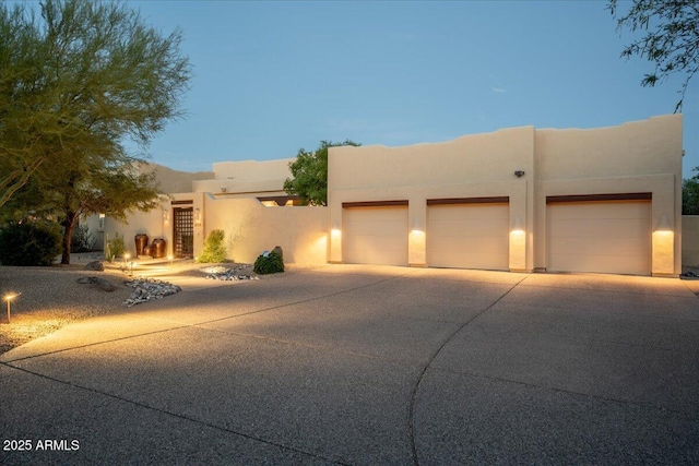 southwest-style home with an attached garage, concrete driveway, and stucco siding