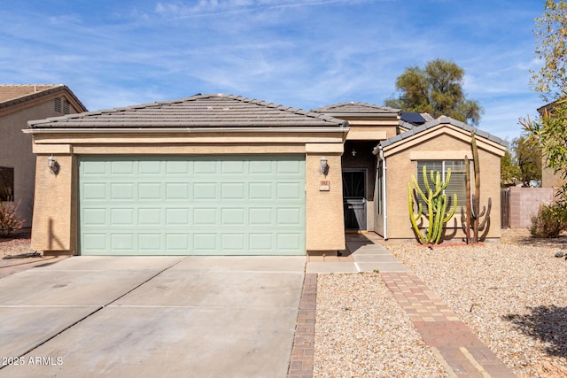 ranch-style home with concrete driveway, a tiled roof, an attached garage, and stucco siding