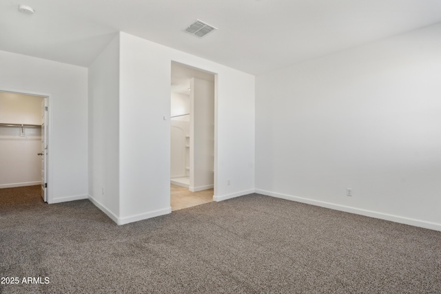 unfurnished bedroom featuring carpet flooring, baseboards, a spacious closet, visible vents, and a closet
