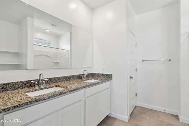 full bathroom with double vanity, baseboards, walk in shower, and a sink