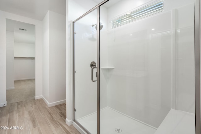 bathroom featuring a shower with shower door and wood-type flooring