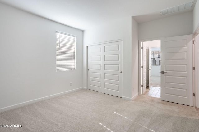 unfurnished bedroom featuring a closet and light colored carpet