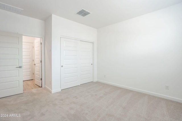 unfurnished bedroom featuring light carpet and a closet