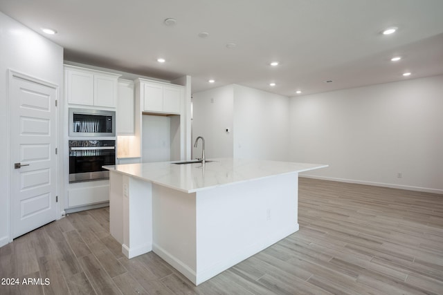 kitchen featuring a large island with sink, light hardwood / wood-style flooring, sink, white cabinets, and appliances with stainless steel finishes