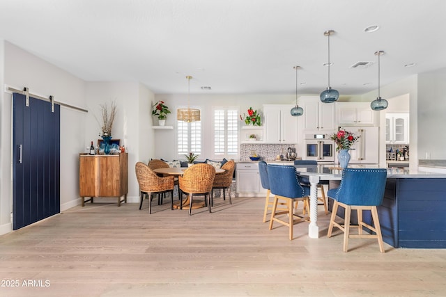 kitchen with a barn door, visible vents, light countertops, white cabinetry, and open shelves