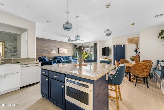 kitchen featuring blue cabinets, light wood-style floors, visible vents, and dishwasher