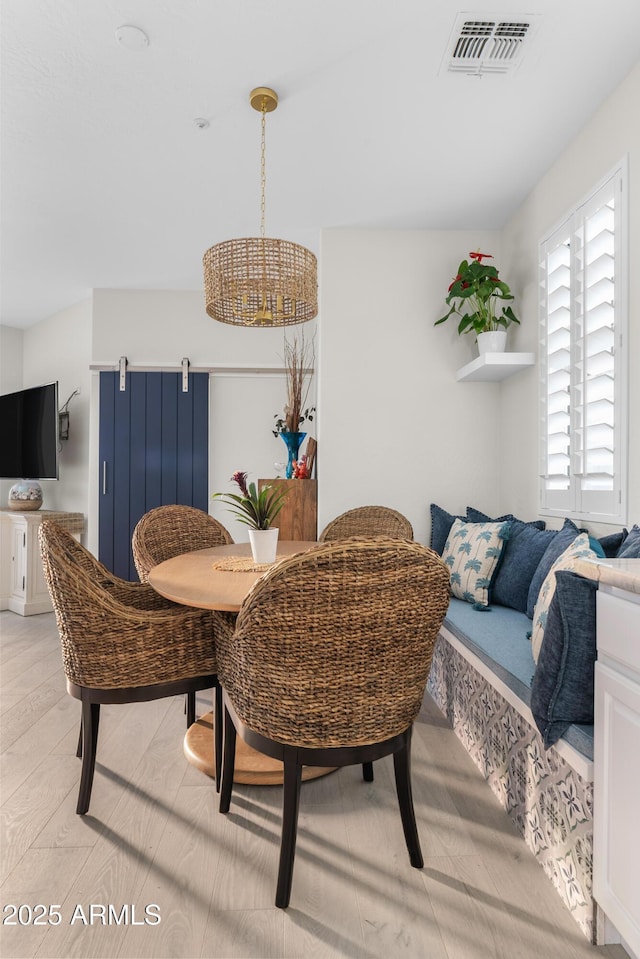 dining space featuring a barn door and visible vents