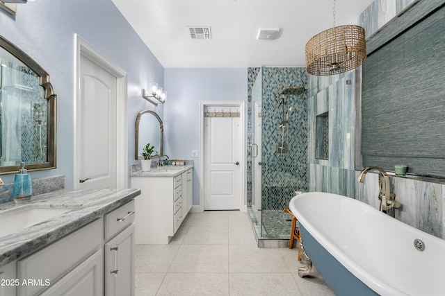 full bath featuring two vanities, a stall shower, tile patterned flooring, and a sink