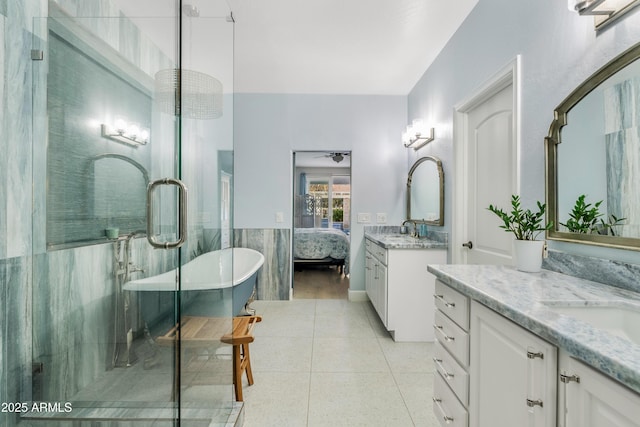 full bathroom featuring tile walls, two vanities, ensuite bathroom, tile patterned floors, and a sink