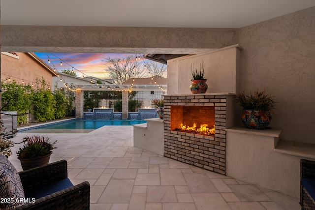 outdoor pool with an outdoor brick fireplace, a patio area, and a fenced backyard