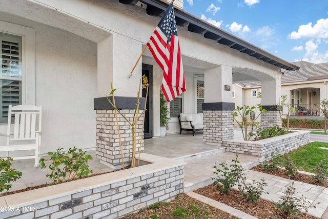 doorway to property featuring a porch and stucco siding