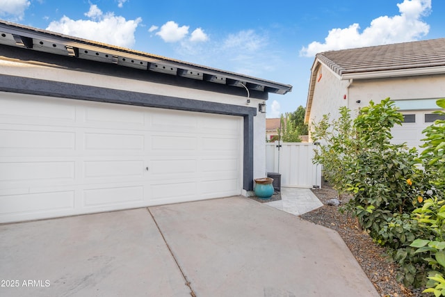 garage featuring concrete driveway and fence