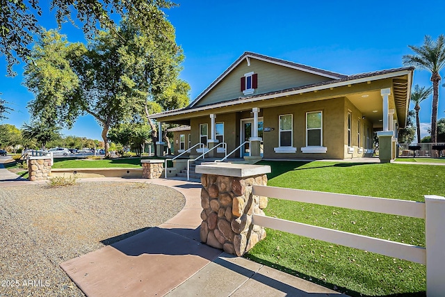 view of front of property featuring covered porch, fence, a front lawn, and stucco siding