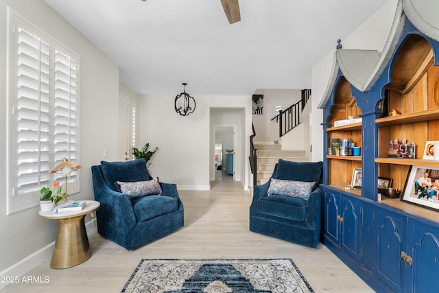 sitting room with stairs, baseboards, and light wood-style floors