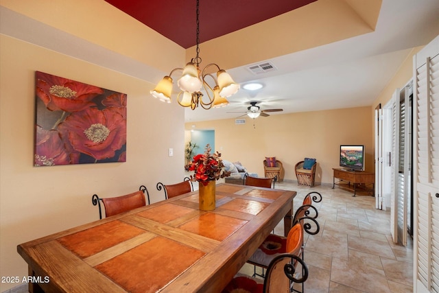 dining area with ceiling fan with notable chandelier, stone finish floor, and visible vents