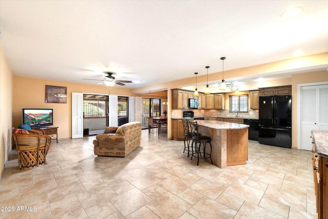 kitchen featuring a center island, a sink, open floor plan, ceiling fan, and black appliances