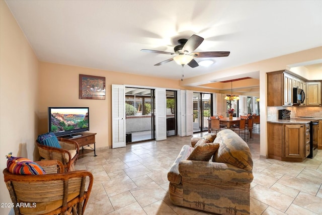 living room with ceiling fan with notable chandelier and baseboards