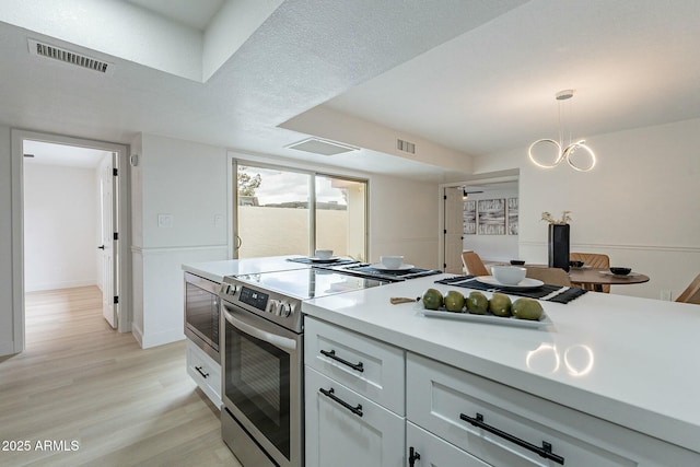 kitchen with light wood-type flooring, visible vents, electric stove, white cabinetry, and light countertops