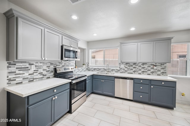 kitchen with decorative backsplash, light countertops, appliances with stainless steel finishes, and a sink