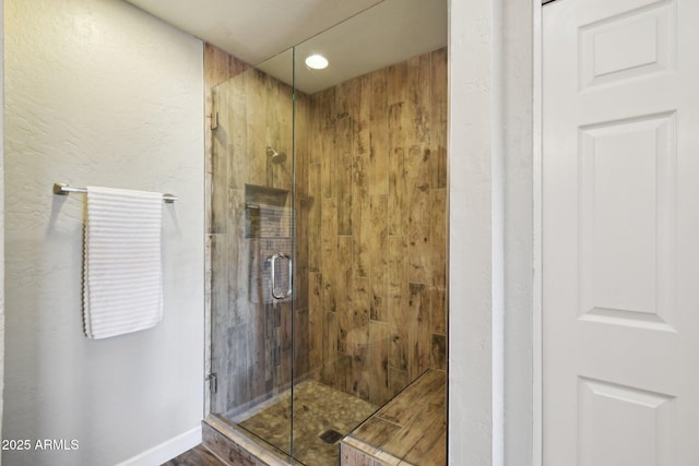 full bath featuring a stall shower and baseboards