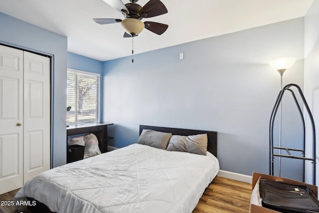 bedroom featuring ceiling fan, a closet, wood finished floors, and baseboards