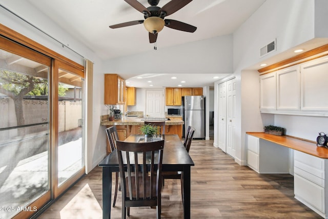 dining room with visible vents, built in study area, vaulted ceiling, wood finished floors, and baseboards