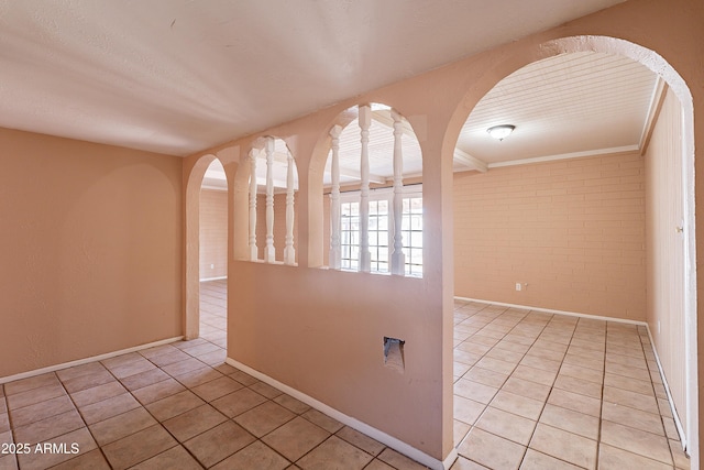 tiled empty room featuring brick wall