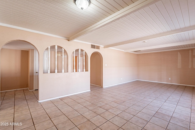 tiled spare room featuring beamed ceiling