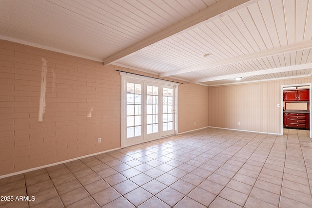 empty room with brick wall, light tile patterned floors, and beam ceiling