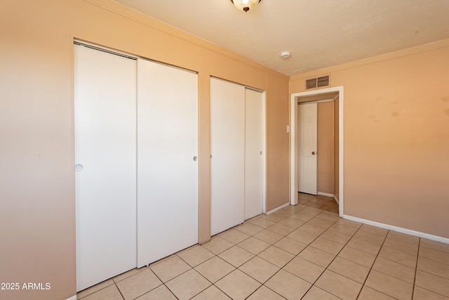 unfurnished bedroom featuring two closets and light tile patterned floors