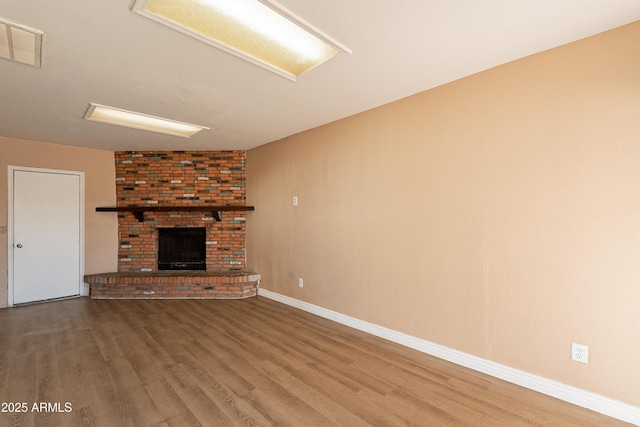 unfurnished living room featuring a brick fireplace and hardwood / wood-style floors