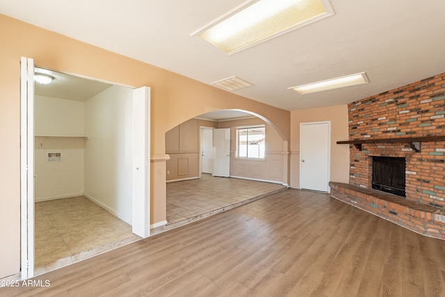 unfurnished living room with a fireplace and light wood-type flooring