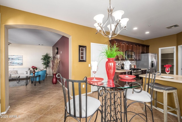 dining area featuring visible vents, arched walkways, a notable chandelier, and light tile patterned flooring