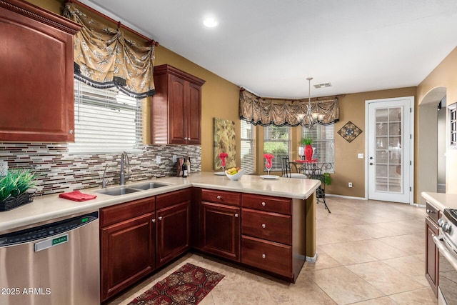 kitchen with a peninsula, stainless steel appliances, a sink, and light countertops