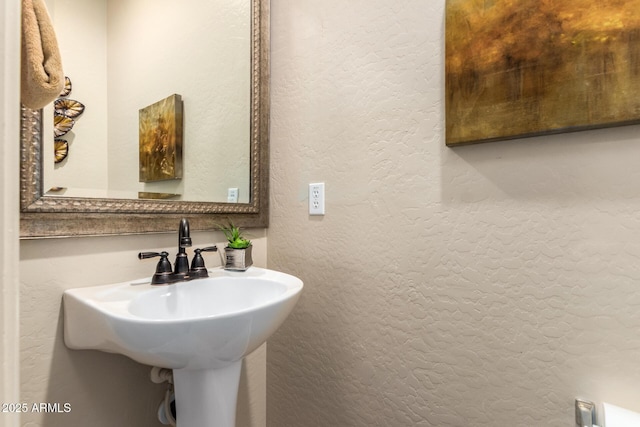 bathroom featuring a textured wall and a sink