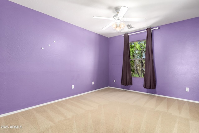 empty room with a ceiling fan, carpet flooring, visible vents, and baseboards