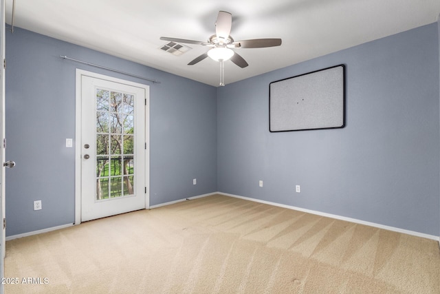 carpeted spare room featuring ceiling fan, visible vents, and baseboards