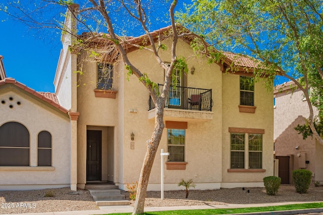 mediterranean / spanish house featuring a tile roof, a balcony, and stucco siding