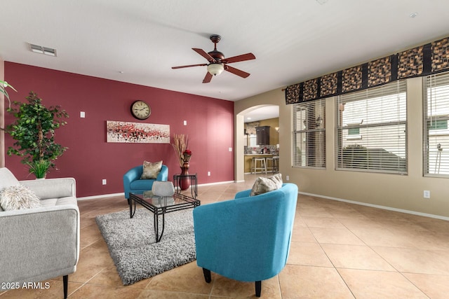 living room with light tile patterned floors, an accent wall, visible vents, and arched walkways