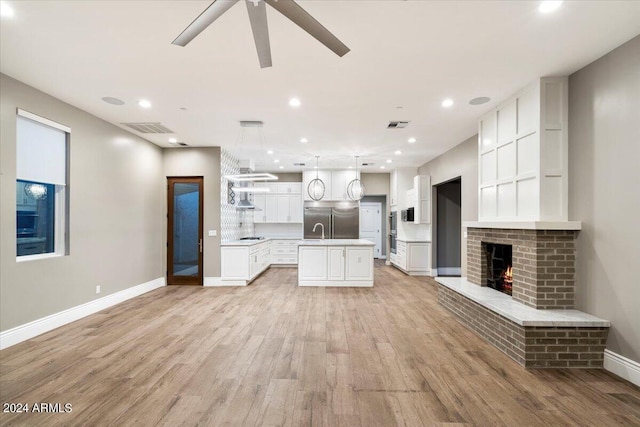 unfurnished living room featuring light wood-type flooring, visible vents, a ceiling fan, a fireplace, and baseboards