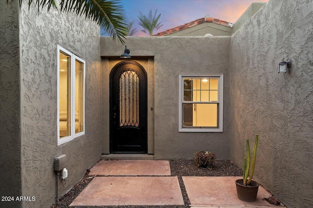 exterior entry at dusk featuring stucco siding