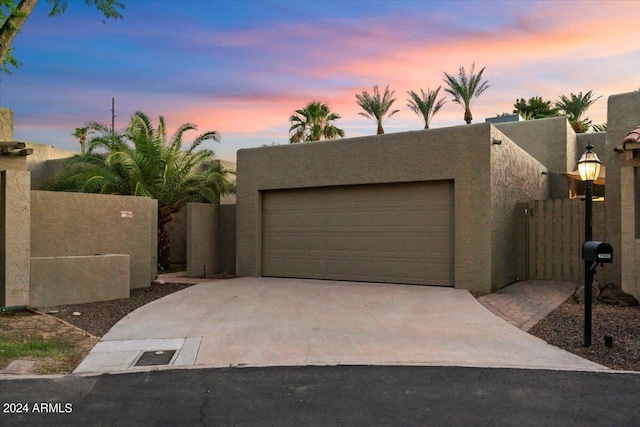 view of front of property featuring stucco siding, driveway, a garage, and fence