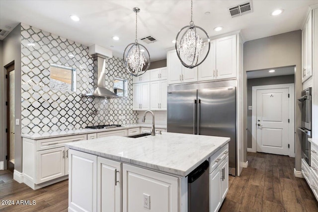 kitchen with visible vents, a notable chandelier, a sink, appliances with stainless steel finishes, and wall chimney exhaust hood