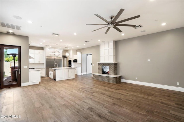 unfurnished living room featuring visible vents, ceiling fan, and wood finished floors