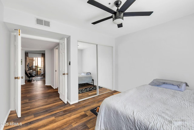 bedroom with baseboards, visible vents, ceiling fan, wood finished floors, and a closet