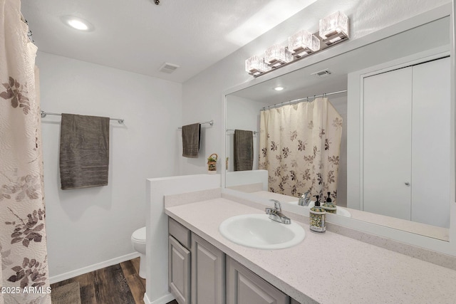 bathroom featuring toilet, wood finished floors, visible vents, vanity, and baseboards